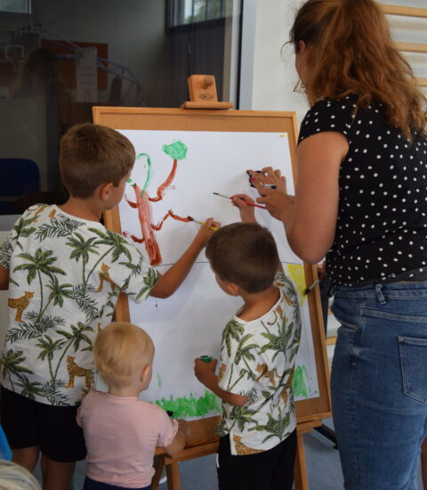 kobieta i troje dzieci stojących tyłem, malują farbami