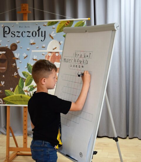 chłopiec pisze na białej tablicy