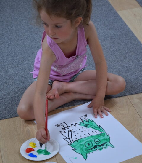 dziewczynka maluje farbami siedząc na podłodze