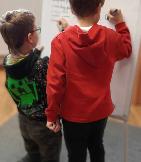 dwóch chłopców pisze na tablicy