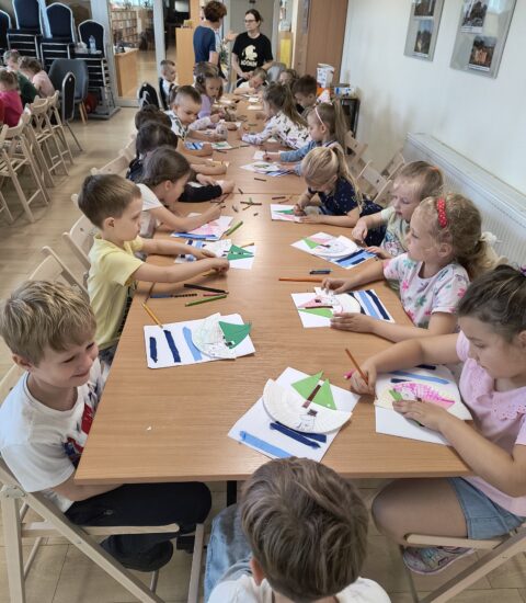 dzieci siedzą przy stołach, rysują