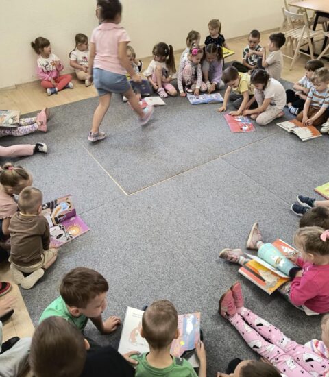 dzieci siedzą na dywanie, oglądają książki