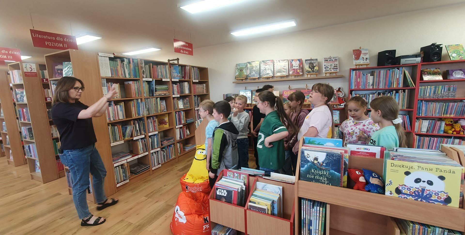 grupa dzieci stoi przy regałach w bibliotece