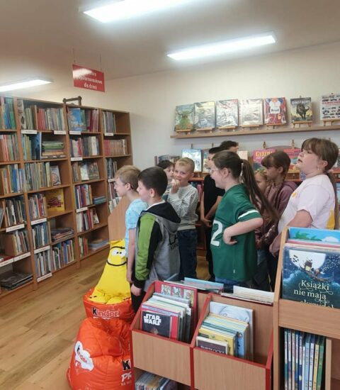 grupa dzieci stoi przy regałach w bibliotece