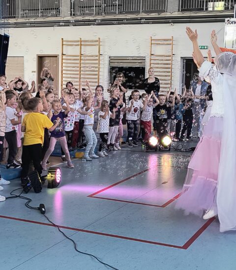 publiczność z aktorami podczas wydarzeniach, dzieci mają podniesione ręce, przed nimi bańki mydlane